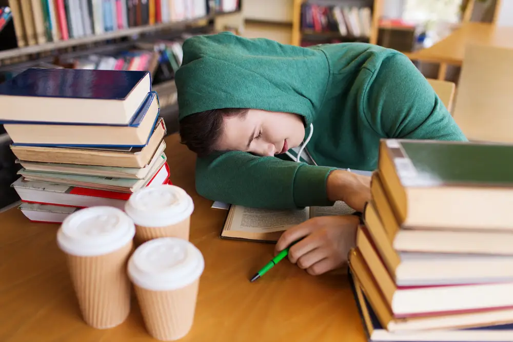unavený student nad knihami s mnoha šálky kávy