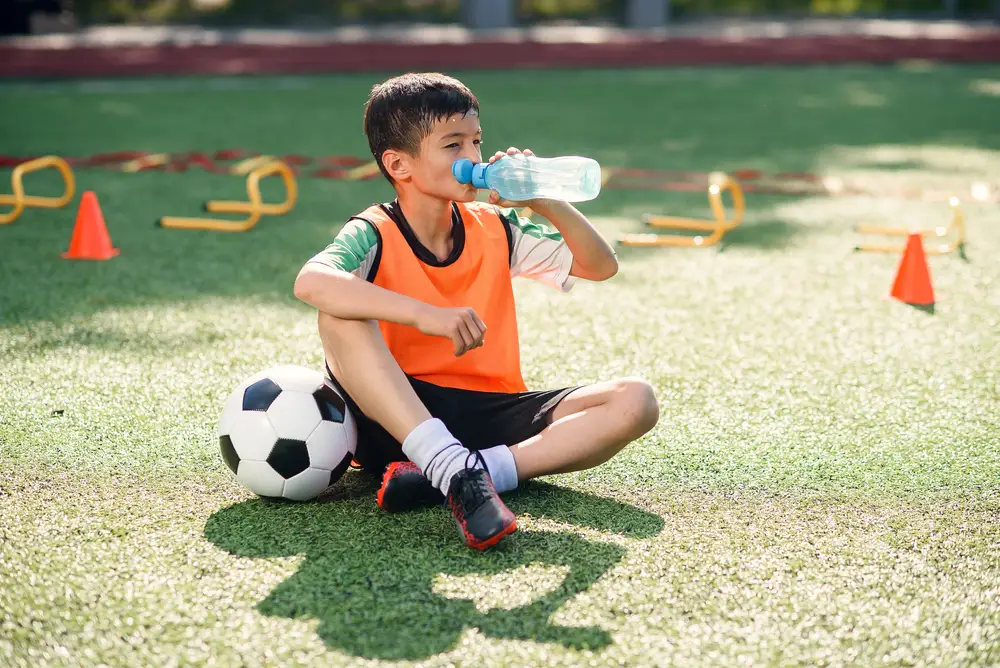 chlapec při fotbalovém tréninku pijící vodu
