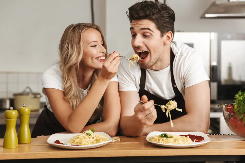 Mladý muž a žena jí špagety s lahůdkovým droždím