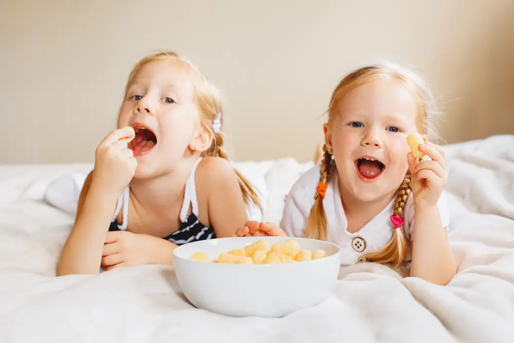 dvě malé dívky jedí křupky