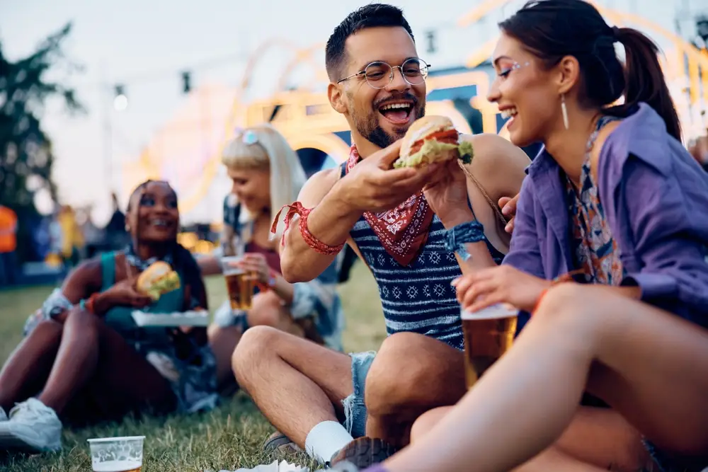 Mladý pár jí hamburger na letním hudebním festivalu.